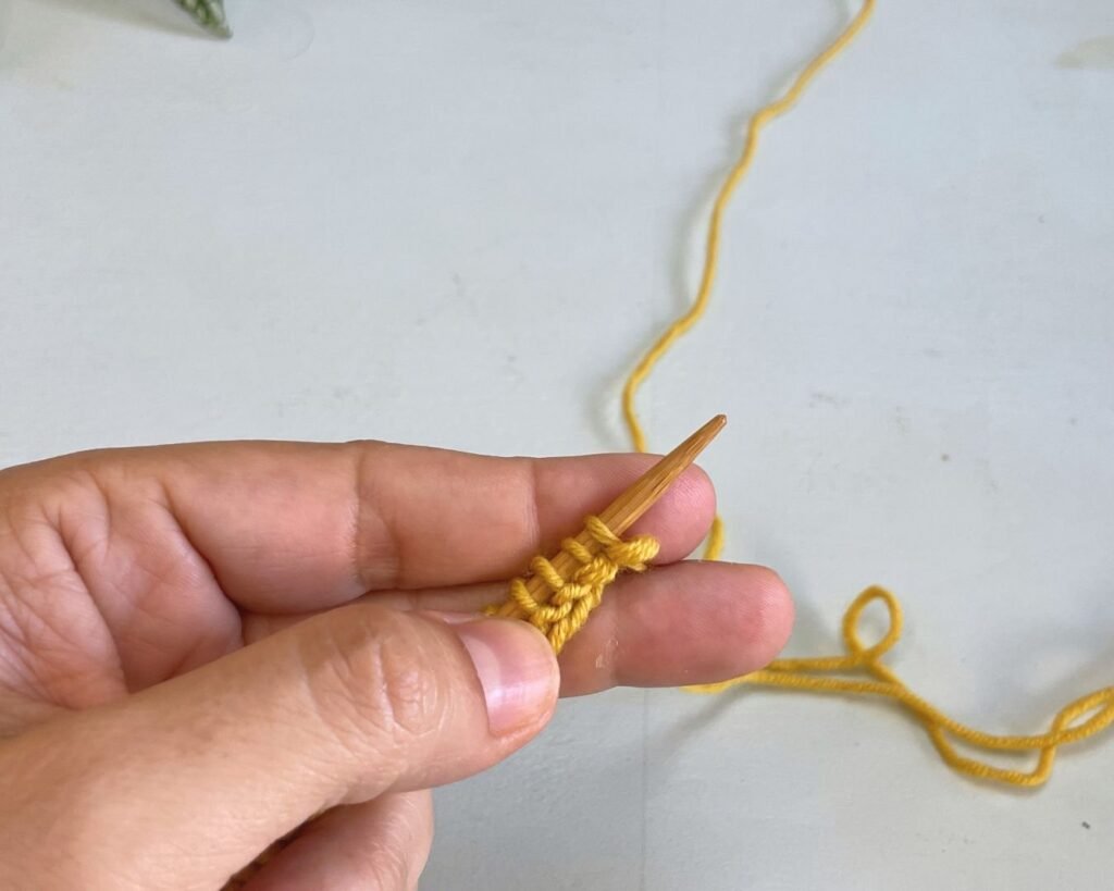 Sujetar la hebra entre los dedos de la mano izquierda antes de comenzar a tejer