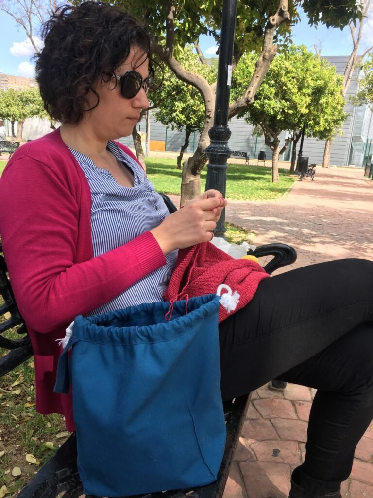 Yo tejiendo en el parque mientras mis hijas juegan